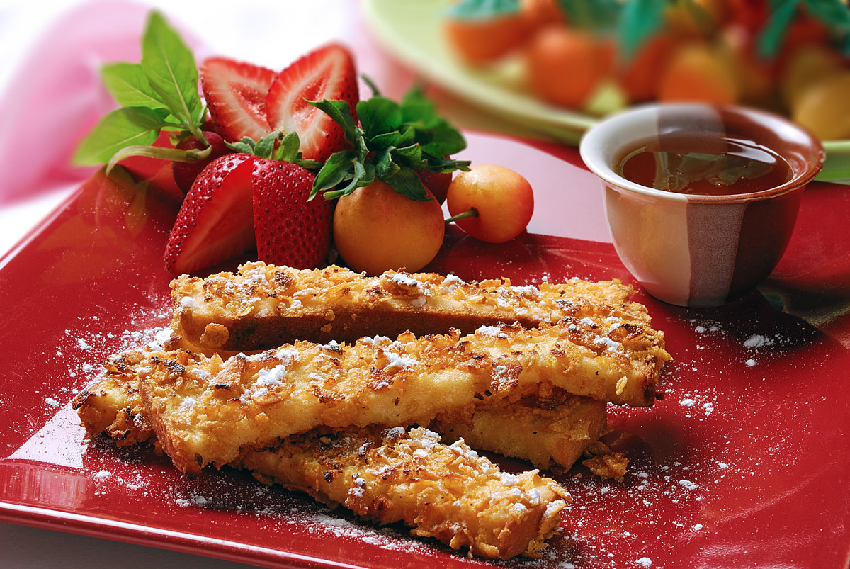 Place corn flakes in a shallow dish. Beat well U.S. liquid eggs with milk, cinnamon and salt. Grease a frying pan with butter and place over medium heat. Dip bread strips in egg mixture and roll in corn flakes until well-coated. Fry the sticks in prepared pan until brown on both sides. Set aside to cool. Dust egg-coated French toast sticks with powdered sugar and serve with honey. Garnish with fruits.